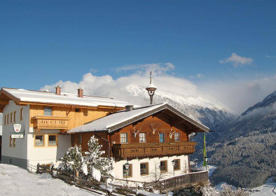 Traditioneller Alpengasthof mit Holzfassade im verschneiten Hohen Tauern Gebirge