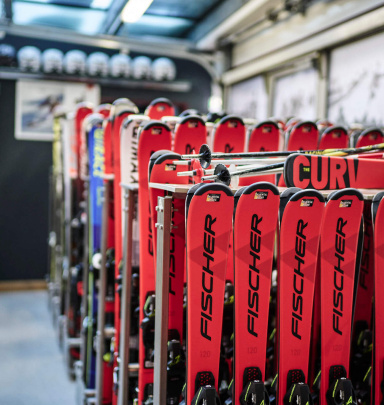 Skis und Stöcke im Skiverleih Bad Hofgastein, umgeben von Helmen und Ausrüstung.
