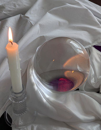 Brennende Kerze und Kristallkugel auf weißem Stoff spirituelle Beratung