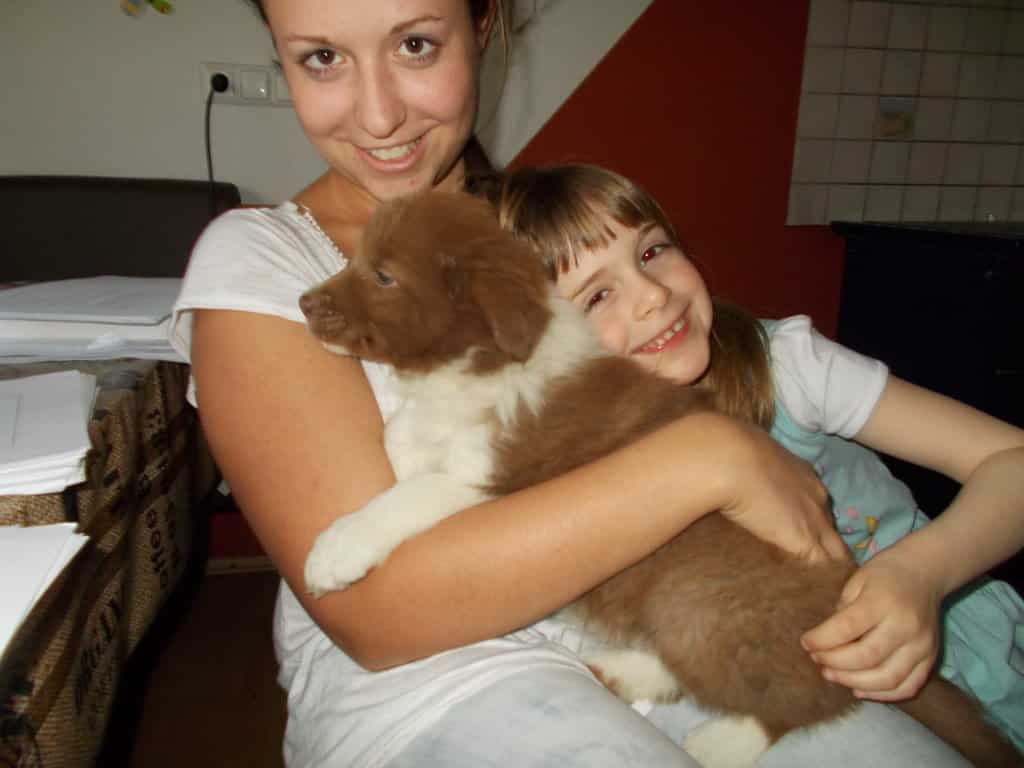 Frau und Mädchen umarmen welpen eines Border Collies auf bio Bauernhof Mostviertel Melk