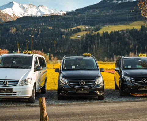 Drei Taxis der Marke Mercedes im malerischen Saalbach Hinterglemm vor Bergen.