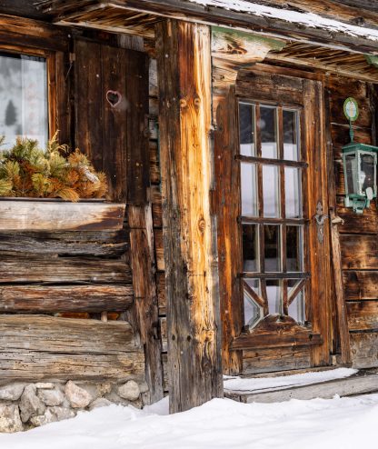 Holzhaus mit Fenster und Tür, umgeben von Schnee in alpiner Atmosphäre der Unterhofalm.