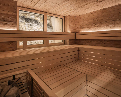 Moderne Sauna aus hellem Holz mit Fenster und indirekter Beleuchtung