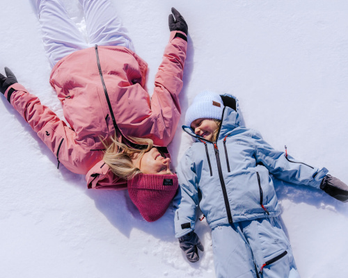 Zwei Personen in Winterkleidung liegen entspannt im Schnee im Lungau