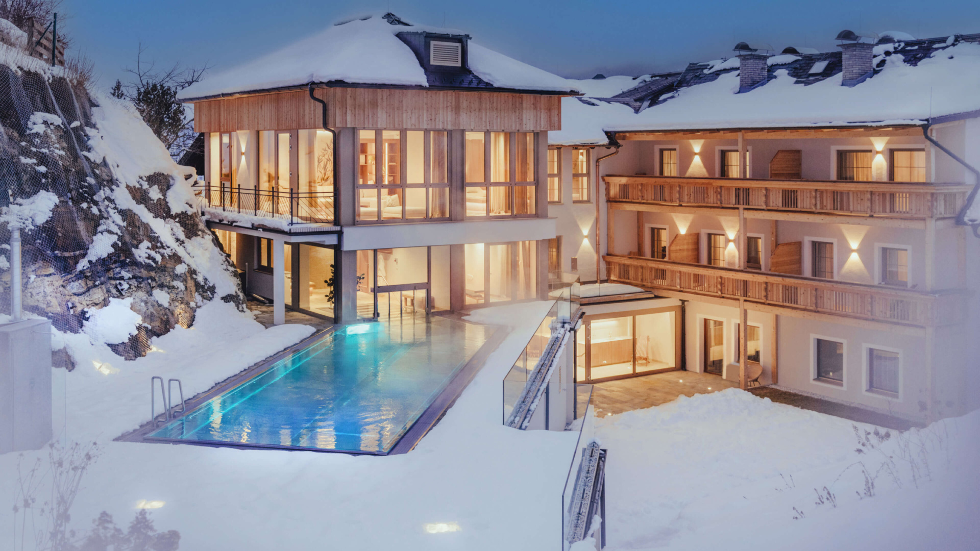 Modernes Wellnesshotel mit beheiztem Außenpool und verschneiten Holzbalkonen im Lungau